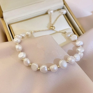 Detailed macro of baroque freshwater pearls and gold beads on pink silk fabric
