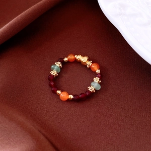 Macro detail of vintage tiger eye agate beaded ring with golden charm on silk