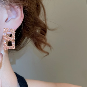 Close-up of 18K gold plated earring with pink zircon in geometric hollow design