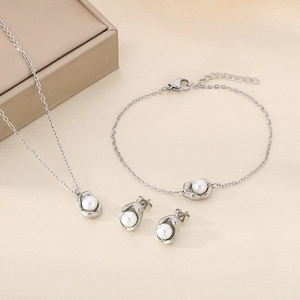 Détail d'un ensemble de bijoux en acier inoxydable argenté avec perles blanches sur tissu