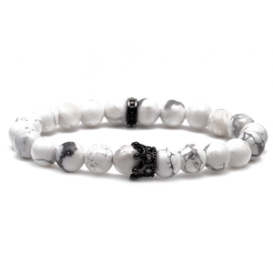 Close-up of white marble bead bracelet with black crown charm and metal spacer detail