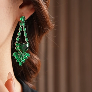 Detail of luxury silver stud earrings featuring green heart-shaped crystal and zircon stones