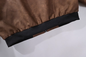 Detailansicht einer dunkelbraunen Wildlederjacke mit schwarzem Rippbündchen und Reißverschluss