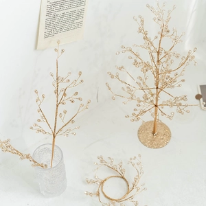 Golden handcrafted beaded decorative branch tree display on white marble surface