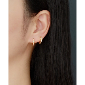 Close-up of gold huggie earrings with sparkling cubic zirconia on a model's ear
