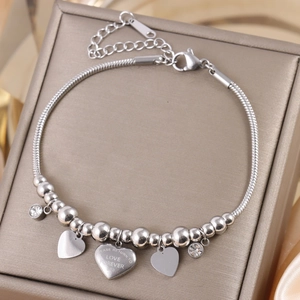 Detailed macro of silver heart pendants on a snake chain bracelet inside a jewelry box