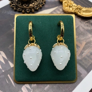 Detail of strawberry earrings with gold hoops and white pearl studs on a display stand