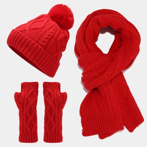 Detailed view of red cable knit texture on winter hat, scarf, and fingerless gloves set