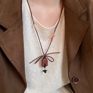 Handmade wooden bear pendant necklace with brown cord, shown on model wearing leather jacket