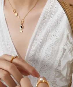Detail of gold star pendant necklace and pearl rings against white lace and mirror