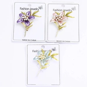 Macro detail of lily flower brooches with enamel petals, pearls and crystals in three colors