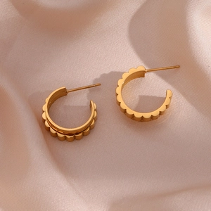 Detailed view of gold C-shaped double-layer gear earrings on champagne silk background