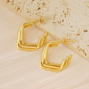 Detail view of gold-plated triple-layered oval hoop earrings on a textured stone base