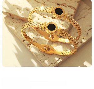 Dettaglio di bracciali a maglia placcati in oro 18K con numeri romani e inserti neri