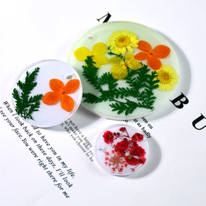 Vue détaillée de trois pendentifs en résine avec fleurs séchées et trous de suspension ronds