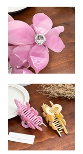 Macro detail of acetate flower hair claws with rhinestone centers on wooden desk