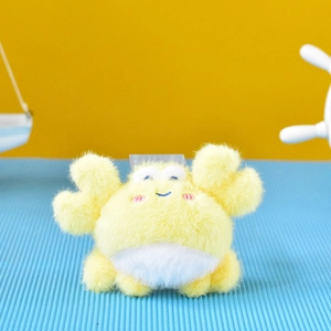 Macro view of a cute yellow fuzzy crab plush toy keychain pendant for bag decoration