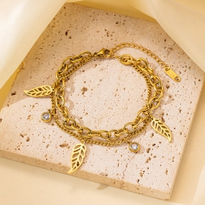 Detalle de pulsera de doble cadena dorada con colgantes de hojas y grabado marca K18