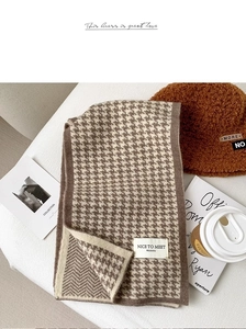 Close-up of brown and beige houndstooth knit scarf with cozy winter accessories on a table