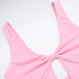 Détail de la robe rose avec un décolleté en V profond et un nœud délicat au centre