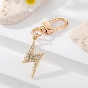 Golden lightning bolt keychain with crystal rhinestones on white platform