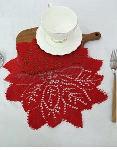 Close-up of red lace placemat with hollow-out knit pattern on a wooden tray