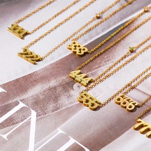 Close-up of gold titanium steel angel number necklaces featuring crystal-studded pendants