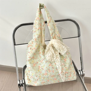 Detail of floral canvas tote bag with white lace bow on a light green floral fabric