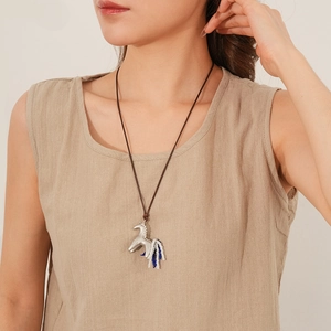 Detail of silver horse pendant necklace with blue and white beaded tassel on brown cord