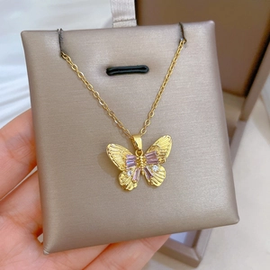 Macro shot of gold butterfly necklace pendant featuring purple zircons and shiny small crystals
