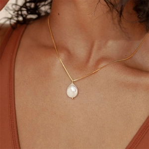 Collier élégant en titane doré avec pendentif en perle d'eau douce naturelle porté par mannequin