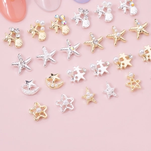 Macro detail of gold and silver hollow star and shell nail charms with pearls and rhinestones