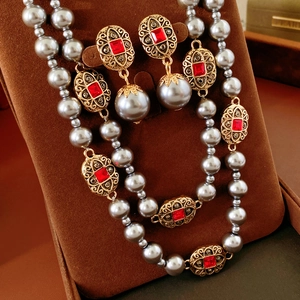 Detailansicht eines Vintage-Goldschmucksets mit roten Edelsteinen und grauen Perlen