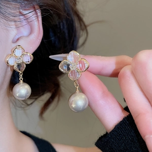 Macro view of gold plated flower stud earring with sparkling crystals and a round pearl