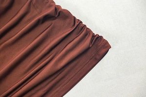 Detail of the double-needle stitching and ruched texture on the brown mini dress hem