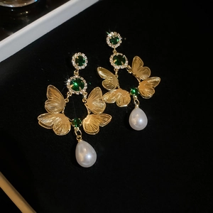 Detail of butterfly wing earring with green gemstone and white teardrop pearl charm