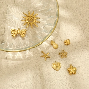 Detailed view of assorted golden charms like starfish and hearts on a glass tray