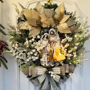Christmas wreath with holy family statue, golden poinsettia, and glowing LED lantern