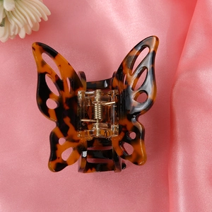 Close-up of tortoise shell butterfly hair clip on pink silk background with white flowers