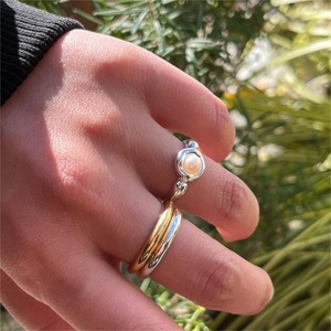 Set of stacked 925 silver rings with pearl and gold bands worn outdoors