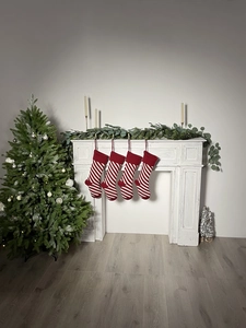 Close-up of four red and white striped knit Christmas stockings hanging on a white fireplace