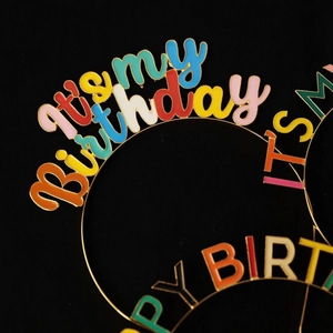 Close-up of colorful enamel letters on a gold metal birthday headband for girls