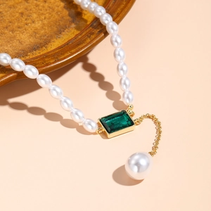 Detailed close-up of multilayered baroque pearl necklace with a green emerald pendant