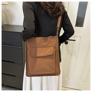 Brown corduroy tote bag showing back view with adjustable strap and front flap pocket