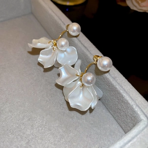 Detail of flower tassel earrings with white petals and pearls on a velvet tray
