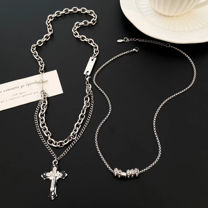 Detail of silver gothic cross pendant and rhinestone bead necklaces on a black surface