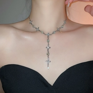 Detailed close-up of crystal cross Y-necklace with teardrop pendant on model