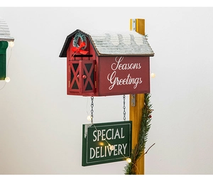 Close-up of red wooden Christmas mailbox with pine branches and warm glowing lights