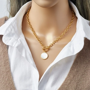 Detail of gold chain necklace with white shell coin pendant and stylish OT toggle clasp