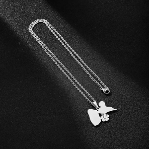 Detail of silver stainless steel butterfly and flower pendant necklace on textured background